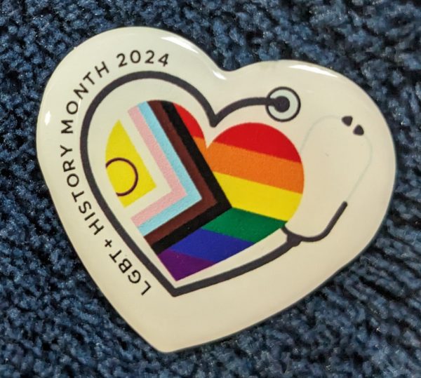 LGBT+ History Month 2024 badge design. A heart containing the progress pride flag, a stethoscope wraps around it.